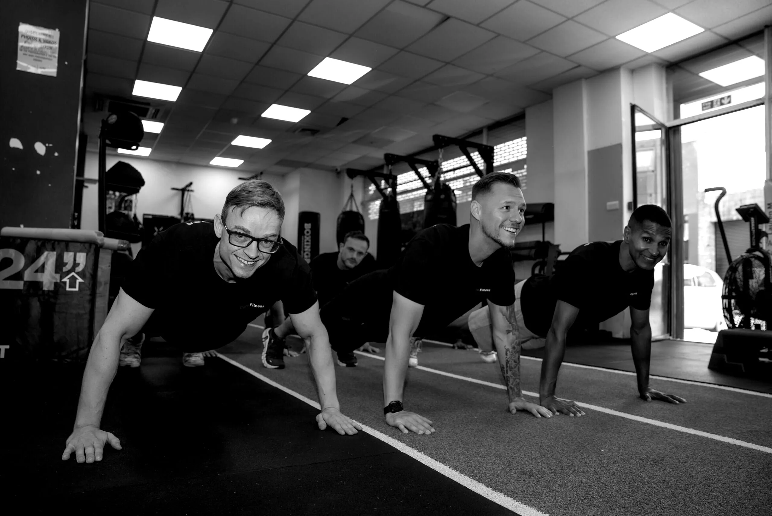 A Bello Fitness class doing press-ups together on the gym turf